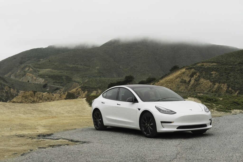 Білий Tesla Model 3 на тлі гір